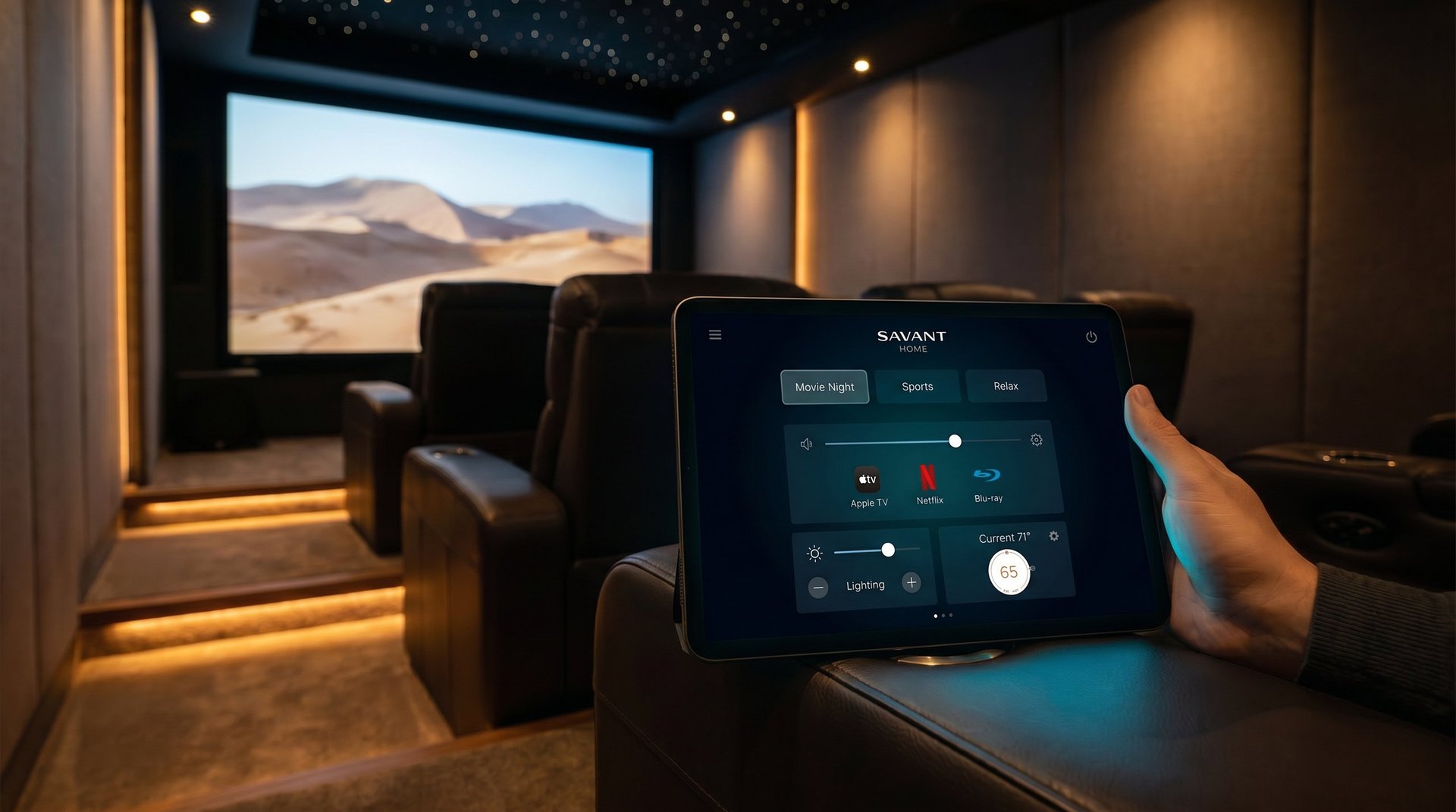 Hand holding tablet displaying smart home controls in a luxury home theater with projected desert landscape on screen
